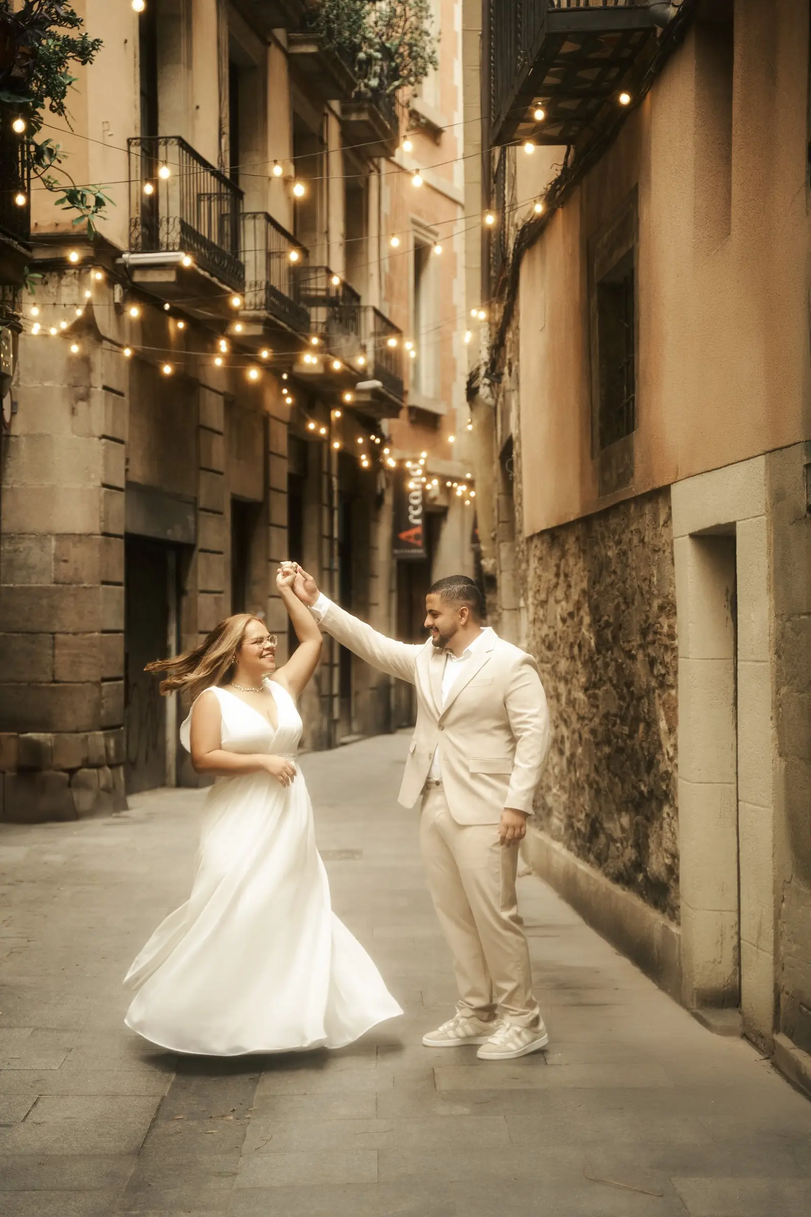 O casal dançando sob varais de luzes em uma rua antiga