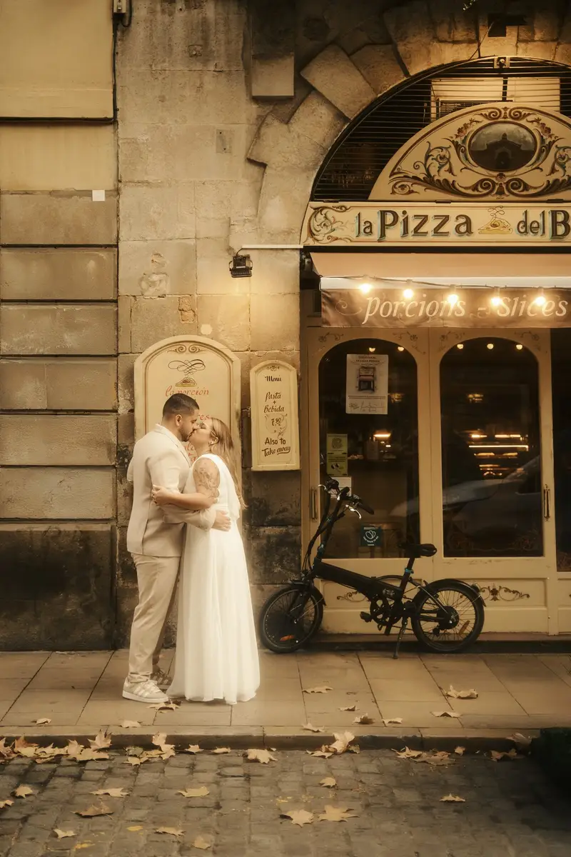 O casal abraçado diante da vitrine iluminada de uma pizzaria, com folhas secas na calçada